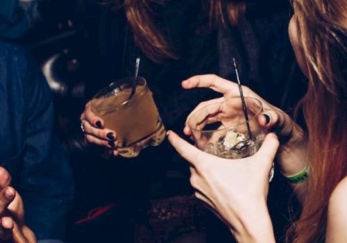 People are in a social setting, holding drinks and laughing, capturing a lively moment.