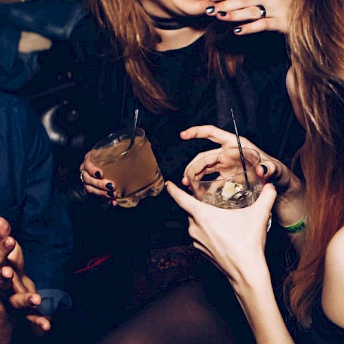 People are in a social setting, holding drinks and laughing, capturing a lively moment.