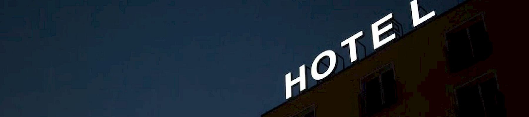 A building with the illuminated word "HOTEL" on its roof, seen against a dark sky.