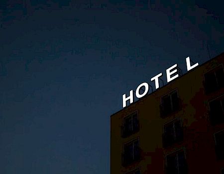 A building with the illuminated word "HOTEL" on its roof, seen against a dark sky.