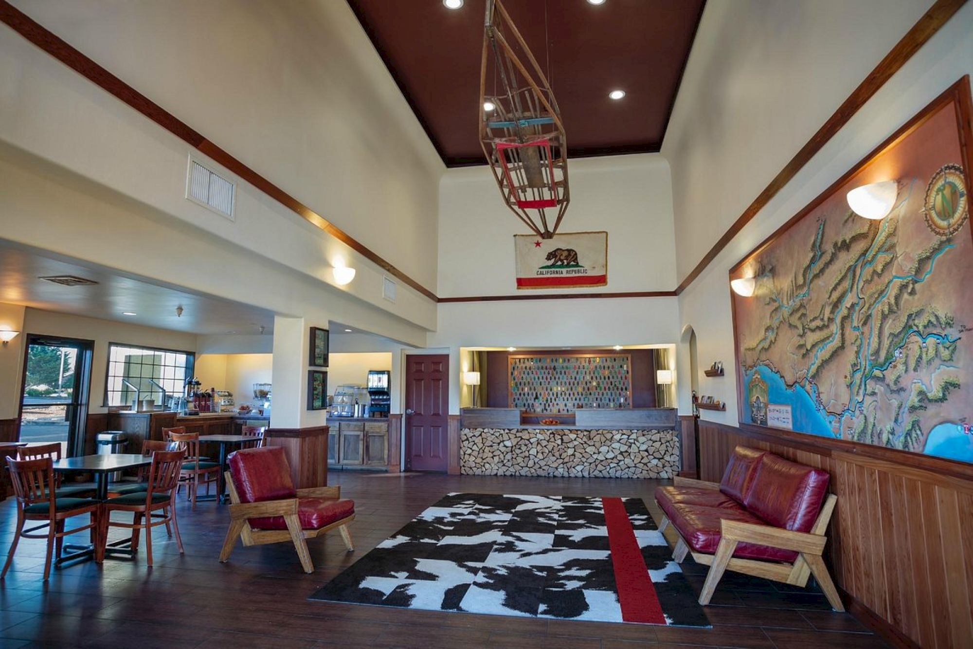 This image shows a lobby with wooden furniture, a map on the wall, and a central reception area. There's a boat-shaped decoration on the ceiling.