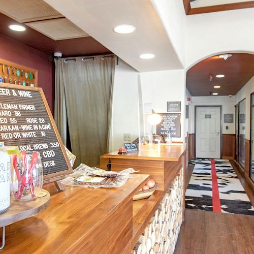 The image shows a reception area with a counter displaying beer and wine options, drinks, and a hallway leading to a door.