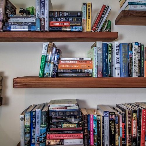 A set of wooden shelves filled with various books organized in a home library setting.