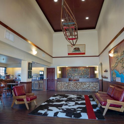A hotel lobby with a rustic theme, featuring wood accents, a map mural, California Republic flag, and a seating area with chairs and tables.