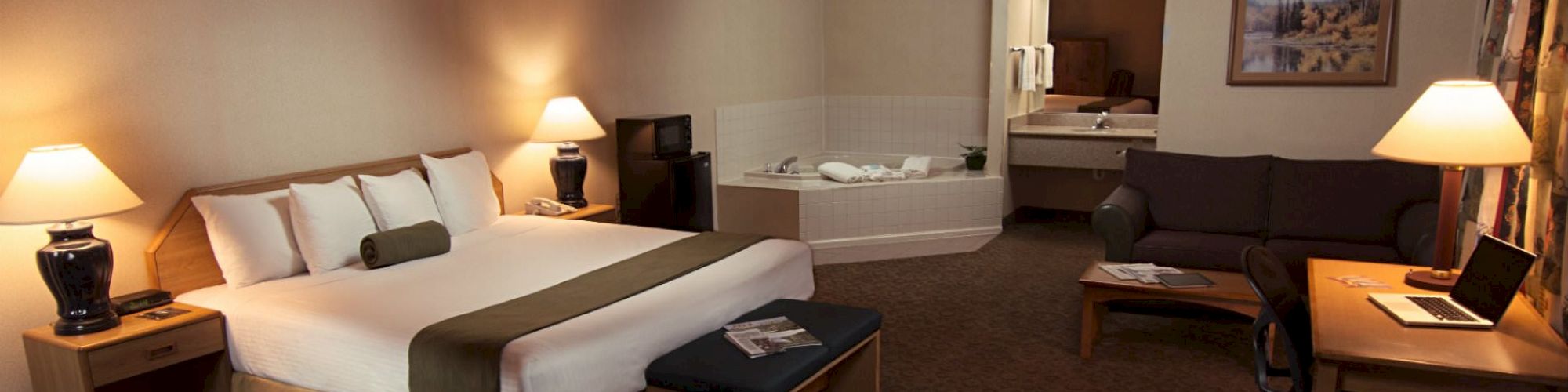 A hotel room with a bed, desk, sitting area, and a whirlpool tub.