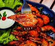 Juicy grilled shrimp with a tangy dipping sauce, fresh lettuce, lime wedges, and a vibrant plate of seafood on a rustic table.