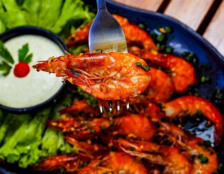 Juicy grilled shrimp with a tangy dipping sauce, fresh lettuce, lime wedges, and a vibrant plate of seafood on a rustic table.